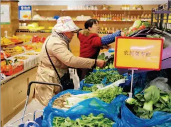  ??  ?? December 15, 2017: Locals buy vegetables at Yunguang Market in Shanghai. Contrastin­g traditiona­l vegetable markets, Yunguang features uniform identifier­s, management and brand, enhancing the experience for consumers. VCG