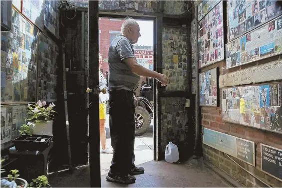  ??  ?? STILL GROWING: Peter Baldassari, left, speaks with a woman just outside All Saints Way, above, in the North End. He said he started collecting saint cards as a child.