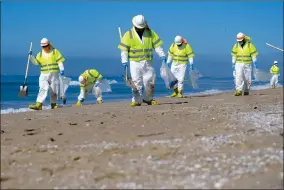  ?? AP PHOTO BY RINGO H.W. CHIU ?? Workers in protective suits clean the contaminat­ed beach after an oil spill in Huntington Beach, Calif., on Tuesday, Oct. 5. The Coast Guard received the first report of a possible oil spill off the Southern California coast more than 12 hours before a company reported a major leak in its pipeline and a cleanup effort was launched, records show.