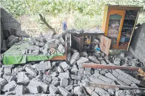  ??  ?? Indonesian and foreign climbers walk down from Rinjani Mountain, where hundreds of them had been stranded when the earthquake struck on July 29. RIGHT A man walks past what remains of a house damaged by the earthquake that struck Sajang village on...