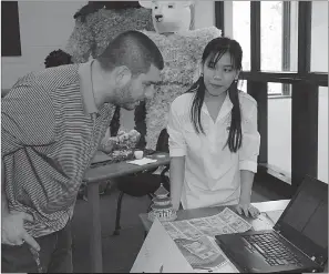  ??  ?? Quynh Tran, a senior at Maurice J. McDonough High School, right, talks about Vietnam with technology teacher David Crisci during a festival hosted by the school’s Internatio­nal Club.