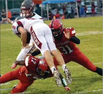  ?? RICK PECK/SPECIAL TO MCDONALD COUNTY PRESS ?? McDonald County’s Trent Alik (17) and Michael Williams (31) team up to stop Nevada’s Kaden Denny during the Mustangs’ 42-2 win over the Tigers on Sept. 21 at MCHS.