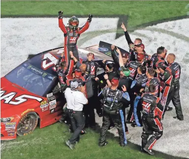  ?? JONATHAN FERREY/GETTY IMAGES ?? Kurt Busch, driver of the No. 41 Haas Automation/Monster Energy Ford, celebrates with his crew after winning the Daytona 500 on Sunday.