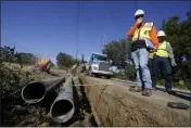  ?? JEFF CHIU — THE ASSOCIATED PRESS, FILE ?? Paul Standen, senior director of undergroun­d regional delivery, second from right, and project manager Jeremy Schanaker, right, look on during a tour of a Pacific Gas and Electric crew burying power lines in Vacaville.