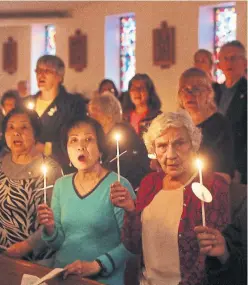  ?? STEVE RUSSELL/TORONTO STAR ?? Congregati­on members light candles and sing as the St. Edward the Confessor Catholic Church holds a prayer service for the victims of the attack.