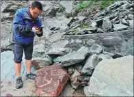  ?? WU XIAOYU / FOR CHINA DAILY ?? A staff member at the Helan Mountain Rock Paintings Conservati­on Park in the Ningxia Hui autonomous region checks rock carvings damaged by flooding this week.