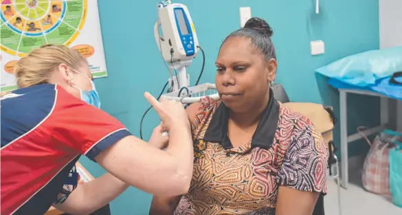  ?? ?? Ngukurr Sunrise Health's Michelle Farrell is given her first dose of the Pfizer Covid-19 vaccine but some communitie­s in the Barkly and Central Australia are lagging far behind. Picture: Thomas Morgan