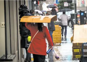  ?? David Paul Morris / Special to The Chronicle ?? At least one pedestrian thought outside the box Friday in an effort to stay dry in San Francisco.