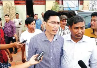  ?? FACEBOOK ?? Former RFA reporters Yeang Sothearin (in blue shirt) and Oun Chhin (back, in white T-shirt) are escorted by officials after being detained for questionin­g in November.