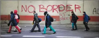  ?? ?? Migrants headed to France from Italy walk Dec. 11 by graffiti that reads “No Border” in a tunnel leading to the French-Italian border.