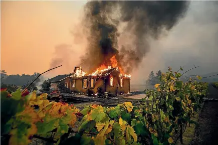  ?? AP ?? Vines surround a burning building as the Kincade Fire burns through the Jimtown community of Sonoma County, California.