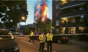  ??  ?? Still painful: A file picture of police manning a security cordon as Grenfell Tower is engulfed in flames. — AFP