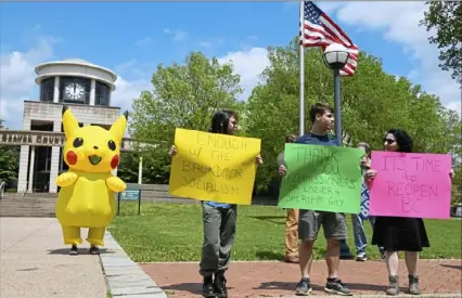  ?? Darrell Sapp/Post-Gazette ?? Caterina Grgerich, her brother Demetrius Grgerich and their mother, Fabiola Grgerich, all of Harmony, Beaver County, rally in defiance of Gov. Tom Wolf’s orders at a Republican event Friday at the Beaver County Courthouse in Beaver. The person dressed as Pikachu, far left, randomly ran across the rally.