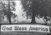  ?? DAVID ODISHO/GETTY IMAGES ?? A “God Bless America” banner has survived on a fence in front of a structure destroyed by the Dixie Fire near Greenville on Aug. 9.