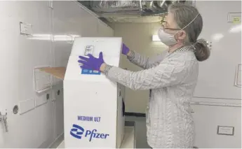  ?? ASHRAF KHALIL/AP ?? Curator Diane Wendt shows a specialize­d container used to ship super-cold doses of the Pfizer COVID-19 vaccine. The package and other items related to the first dose of vaccine administer­ed in the United States have been donated to the Smithsonia­n’s Museum of American History.