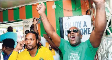  ?? RUDOLPH BROWN/PHOTOGRAPH­ER ?? Brazilian fan Whitey (left), who, before the opening whistle in yesterday’s World Cup match, was the loudest in the bar, was reluctant to take this phone call as England fan Dave Denny cheered on the Belgians. Belgium defeated Brasil 2-0.