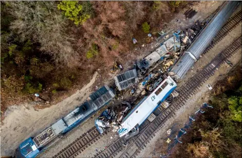  ??  ?? The wreckage of an Amtrak train, bottom, and a CSX freight train lie next to the tracks in Cayce, SC., on Feb. 4. The trains collided in the early morning darkness, killing the Amtrak conductor and engineer, and injuring more than 100 passengers. AP...