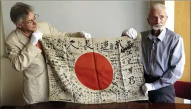  ?? DON RYAN — THE ASSOCIATED PRESS ?? In this Monday photo, WWII veteran Marvin Strombo, right, and Obon Society executive director Rex Ziak hold up a Japanese flag with names written on it in Portland, Ore. Strombo recovered the flag from a dead Japanese soldier in the Pacific more than...