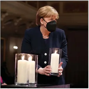  ?? (AP/Michael Sohn) ?? German Chancellor Angela Merkel holds a candle Sunday during a memorial event in Berlin for the thousands of citizens who have died from covid-19. More photos at arkansason­line.com/419covid/.