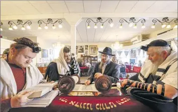  ?? Paul Kuroda For The Times ?? JACOB HALLOVANY, left, Junior Rabbi Alon Chanukov and Rabbi Bentziyon Pil pray with others at the Schneerson Jewish Center in San Francisco. Worship continues amid lingering anxiety over a recent shooting.