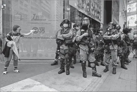  ?? VINCENT YU/AP PHOTO ?? Riot police stand guard as a woman tries to cross the street Wednesday in the Causeway Bay district of Hong Kong. Hong Kong police massed outside the legislatur­e complex Wednesday, ahead of debate on a bill that would criminaliz­e abuse of the Chinese national anthem in the semiautono­mous city.