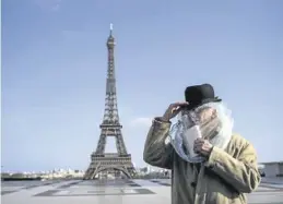  ?? EFE / JULIEN DE ROSA ?? Un hombre cubierto con una bolsa de plástico lee un libro, en París.