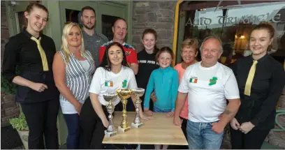  ??  ?? Serena Pierce (by trophies) and her coach and dad, Tony celebrate her recent world title wins in Matla with the sponsors and sponsor organisers and staff members from the Auld Triangle, Shauna & Micheala, where it all started. Picture: John Delea.