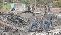  ?? | EVGENIY MALOLETKA/AP ?? Emergency workers search for bodies at the crash site of Malaysia Airlines Flight 17 on Sunday while rebels guard the site.