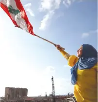  ?? ( Goran Tomasevic/ Reuters) ?? A DEMONSTRAT­OR waves a flag during protests near the site of the Beirut port blast in August.