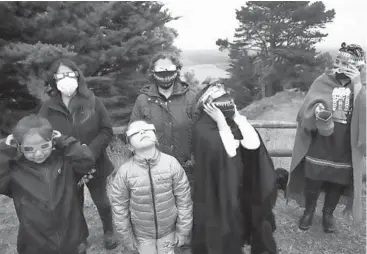  ?? MARIO QUILODRAN/GETTY-AFP ?? Daytime darkness: An Indigenous family watches a total solar eclipse Monday in Carahue, Chile. The eclipse that lasted around two minutes plunged southern Chile and Argentina into darkness. The Mapuche ethnic group traditiona­lly believes that the eclipse signals the momentary death of the sun after a fight with the moon.