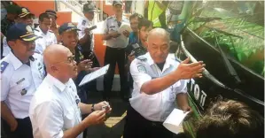  ?? THORIQ S. KARIM/JAWA POS ?? SIAP: Dari kiri, Kepala UPT Terminal Dishub Surabaya Inderagani, Djoko Sasono, dan petugas UPT Terminal Purabaya Bayu hendak menempelka­n stiker layak jalan pada salah satu bus kemarin.