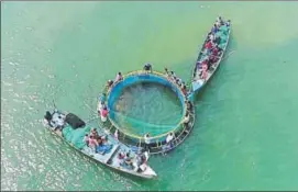  ?? HT PHOTO ?? A cage is installed in the sea using air balloons or air bags under cage farming and then fish seeds are deposited in it. (Below) Men pull out fish from the cage. Marine experts say in open cage fish farming, production is 70% times more than the...