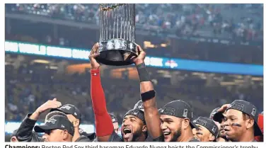 ?? — Reuters ?? Champions: Boston Red Sox third baseman Eduardo Nunez hoists the Commission­er’s trophy after defeating the Los Angeles Dodgers in game five of the 2018 World Series at Dodger Stadium in Los Angeles.