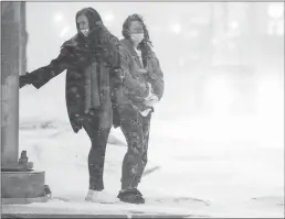  ?? Tribune News Service/the Dallas Morning News ?? Miryea Gist (left) and Mikaela Dudley wait in heavy snow to cross Mockingbir­d Lane near Dallas Love Field as a winter storm brings snow and freezing temperatur­es to North Texas on Feb. 14 in Dallas.
