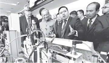  ??  ?? Prime Minister Tun Dr Mahathir Mohamad listens to an explainati­on from Bosch Drive and Automation Group chief executive officer Michel Gunawan (second right) during his visit to booths at the launch of the National Policy on Industry 4.0 at Menara MITI yesterday. — Bernama photo