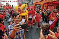  ??  ?? People take photos with young lion dancers performing in Chinatown in Bangkok on the first day
of the Lunar New Year.