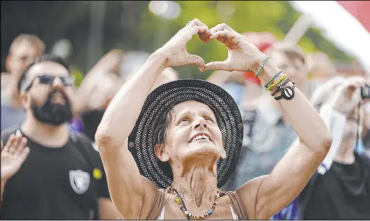  ?? Kay Nietfeld The Associated Press ?? A participan­t forms a heart with her hands Saturday during a demonstrat­ion in Berlin. Tens of thousands gathered at Brandenbur­g Gate before heading down the Unter den Linden boulevard in a show of defiance against coronaviru­s prevention measures.