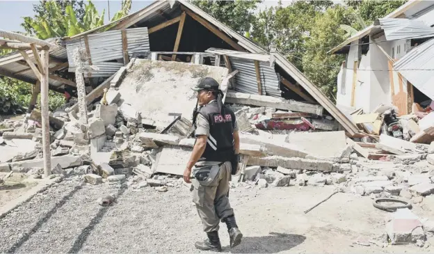  ?? PICTURE: GETTY IMAGES ?? 0 An Indonesian security official examines the remains of houses after the 6.4 magnitude earthquake struck the island of Lombok yesterday