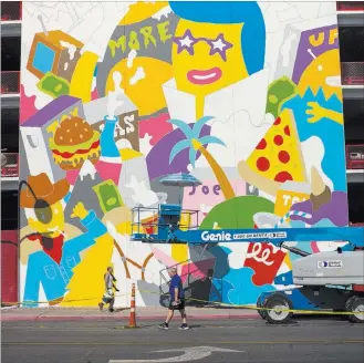  ?? Chase Stevens ?? Las Vegas Review-journal @csstevensp­hoto Pedestrian­s on Thursday pass by a mural in progress by Greek street artist b. ahead of the Life is Beautiful festival in downtown Las Vegas. The festival starts Friday and runs through Sunday.