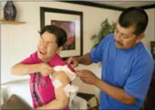  ?? JAY JANNER/AUSTIN AMERICAN-STATESMAN VIA AP ?? Joaquin Ramirez checks on the gunshot wound on Rosanne Solis’ left arm at their home in Sutherland Springs on Tuesday. The two survived the mass shooting at First Baptist Church in Sutherland Springs.