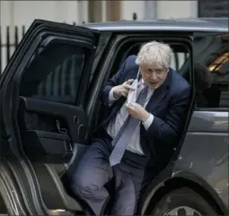  ?? Rob Pinney/Getty Images ?? Prime Minister Boris Johnson removes his face mask as he returns to Downing Street on Jan. 25 in London.