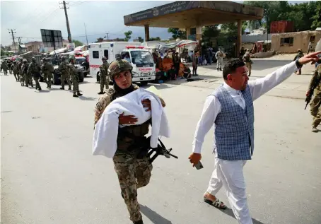  ?? AP ?? An Afghan security officer carries a baby after gunmen attacked a maternity hospital in Kabul on Tuesday. Gunmen stormed the hospital in the western part of Kabul.