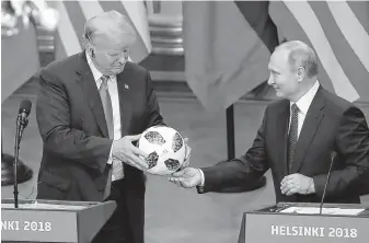  ??  ?? Russian President Vladimir Putin presents a soccer ball to President Donald Trump at their news conference Monday. Trump said he’d give it to his 12-year-old son, Barron, a soccer fan. Then he tossed the ball to his wife, Melania, who was sitting in the front row.