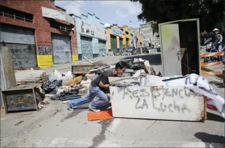  ?? ARIANA CUBILLOS — THE ASSOCIATED PRESS ?? An anti-government demonstrat­or pushes an old refrigerat­or to make a barricade on Saturday to protest against President Nicolas Maduro’s plan to rewrite the constituti­on in Caracas, Venezuela. The country is voting today on Maduro’s plan despite protests and the threat of U.S. sanctions.