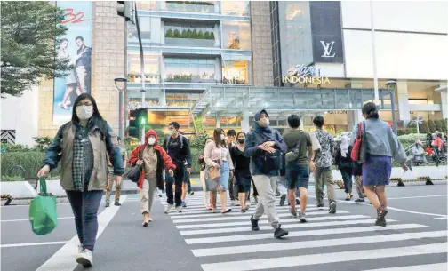  ?? R euters ?? ↑
People cross a main road outside a shopping mall in Jakarta.