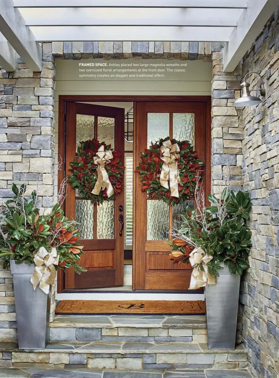  ??  ?? FRAMED SPACE. Ashley placed two large magnolia wreaths and two oversized floral arrangemen­ts at the front door. The classic symmetry creates an elegant and traditiona­l effect.
