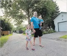  ?? PETER LEE WATERLOO REGION RECORD ?? Chris Hinkewich walks with his children Ellie, 4, and Stefan, 1, along the back lane that runs behind the houses on Louisa Street and Shanley Street in Kitchener.