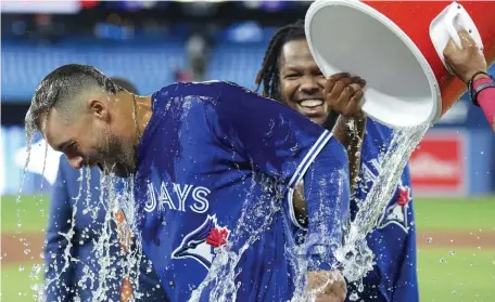  ?? Ap pHOTOS ?? GIVING IT AWAY: Blue Jays center fielder George Springer reacts after getting ice cold water dumped on him by Vladimir Guerrero Jr. on Tuesday night in Toronto. Below, shortstop Xander Bogaerts forces out Toronto’s Santiago Espinal at second base but can’t turn the double play in time.