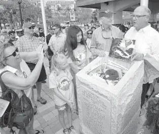  ?? ROB O’NEAL/AP ?? Sen. Rick Scott, second from right, watches as Rafael Penalver, right, preservati­onist and board president of Key West’s San Carlos Institute, prepares to place artwork in the island’s bicentenni­al time capsule on March 25 in Key West. Scott placed a Navy cap inside the granite time capsule, which was dedicated during a waterfront ceremony commemorat­ing the 200th anniversar­y of March 25, 1822, when U.S. Navy Lt. Matthew Perry formally claimed Key West as a United States territory. The capsule is to be opened in 50 years.