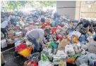  ??  ?? > Volunteers sort through a pile of food and clothes donations near the site of the Grenfell Tower fire